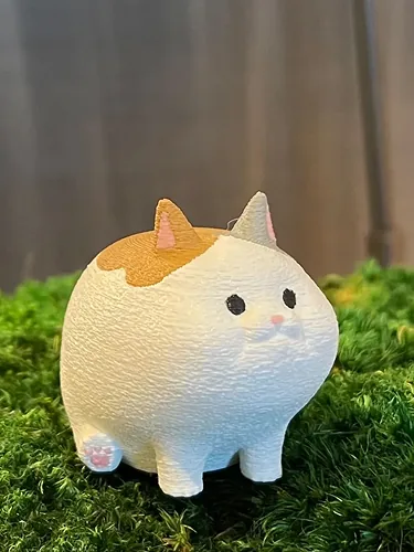 Chubby calico cat figure on grass